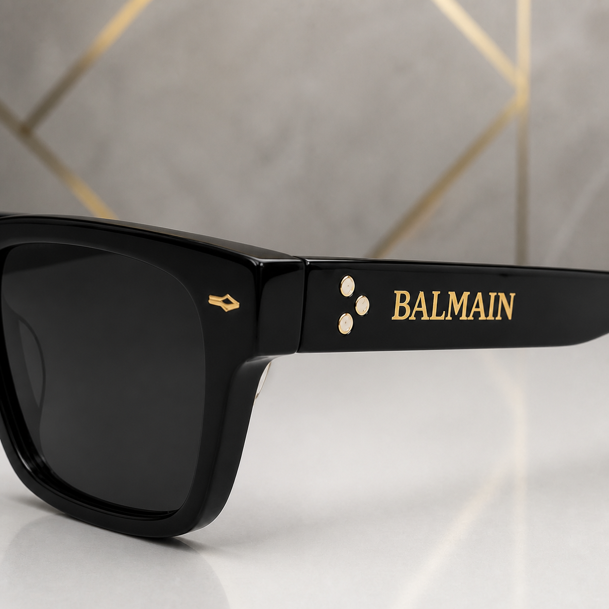 Close-up of Balmain sunglasses gold emblem, studs and temple wordmark