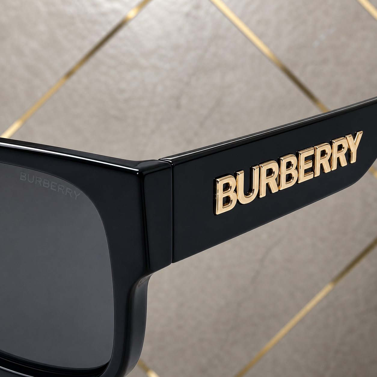 Close-up of Burberry sunglasses gold temple wordmark and glossy black hinge