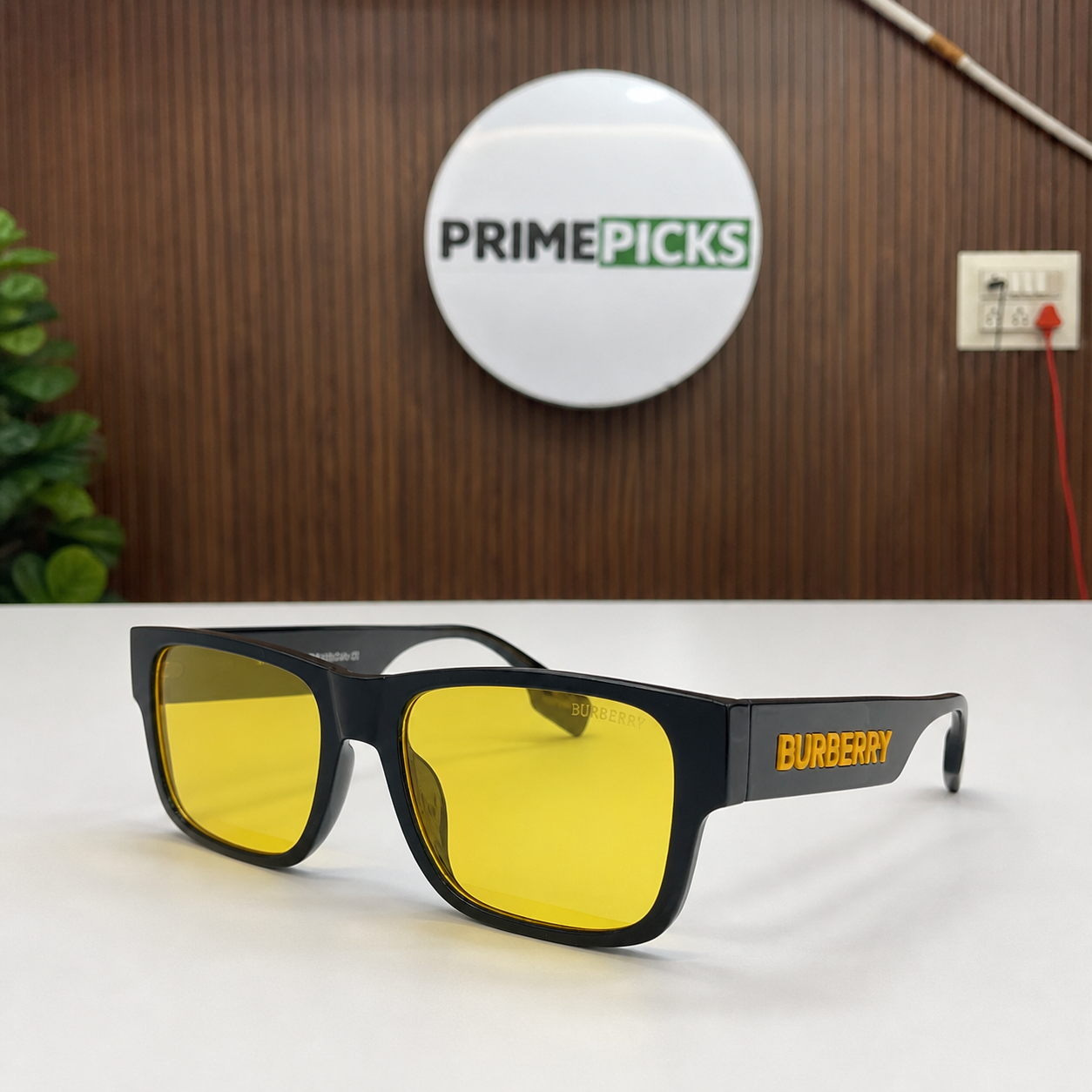 Burberry black rectangular sunglasses with yellow lenses beside the PrimePicks sign