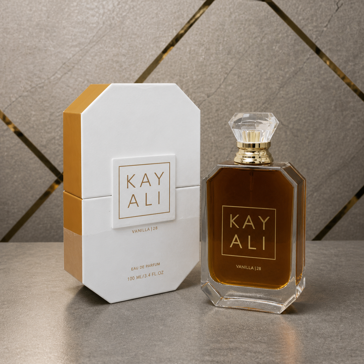 Kayali Vanilla | 28 Eau de Parfum 100ml against the PrimePicks grey stone and gold wall