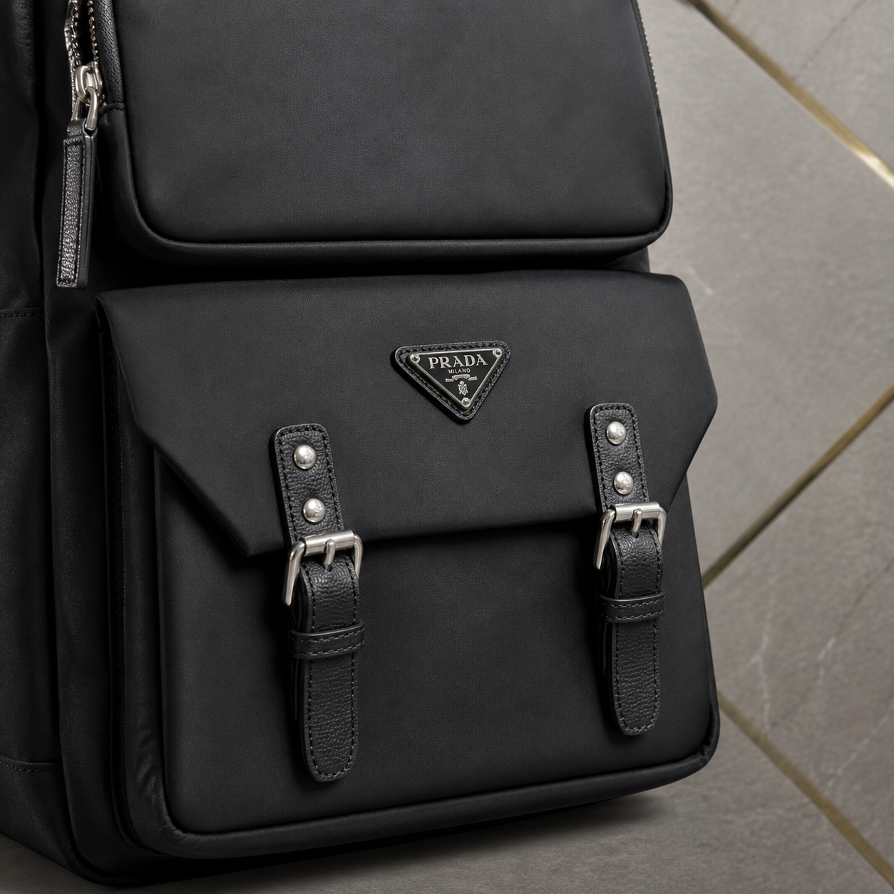 Close-up of Prada black Re-Nylon backpack flap, triangle badge and buckle hardware