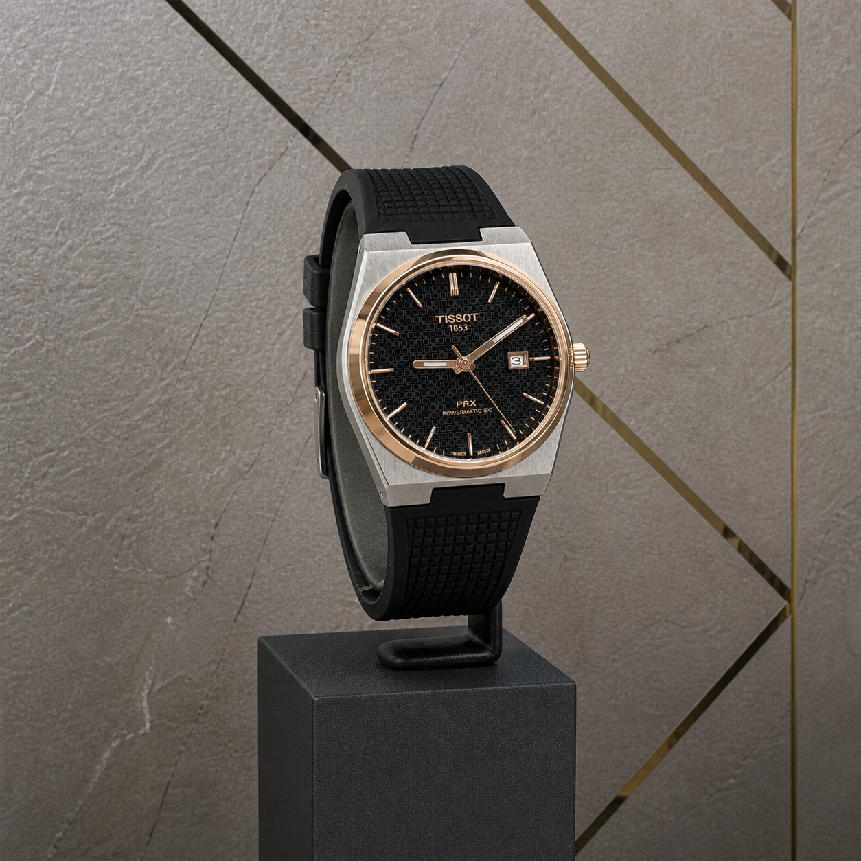 Tissot PRX men’s watch with black textured dial displayed against the grey and gold Primepicks office wall