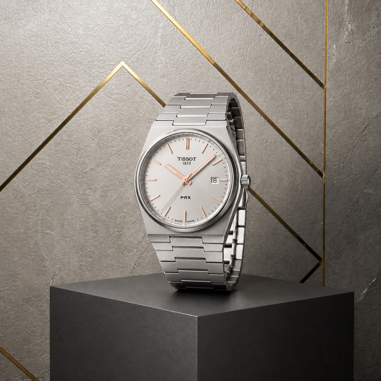 Tissot PRX silver dial stainless-steel watch three-quarter view on grey and gold office wall