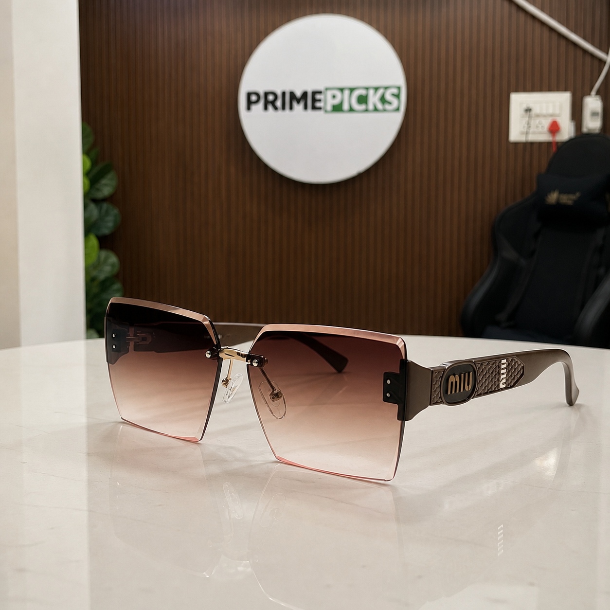 Miu Miu brown-temple oversized rimless square sunglasses with bronze-tone medallions and brown-to-rose gradient lenses, PrimePicks office lifestyle view