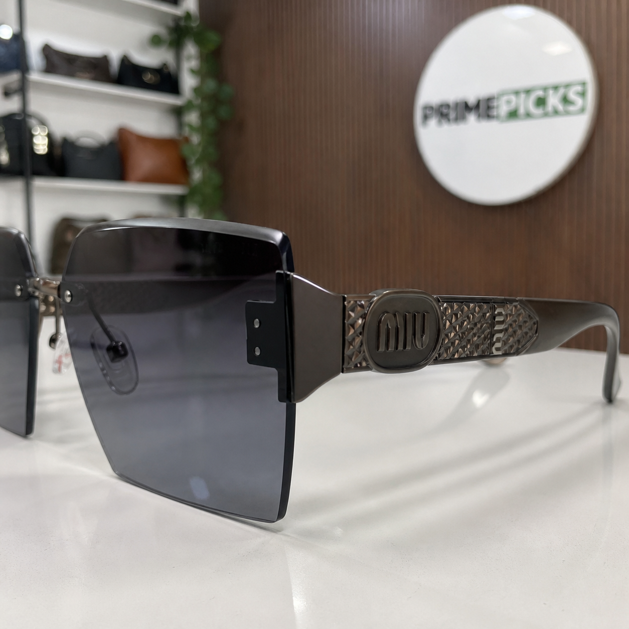 Miu Miu dark brown-temple oversized rimless square sunglasses with gunmetal-tone hardware and dark smoke-blue gradient lenses, temple medallion and textured panel detail