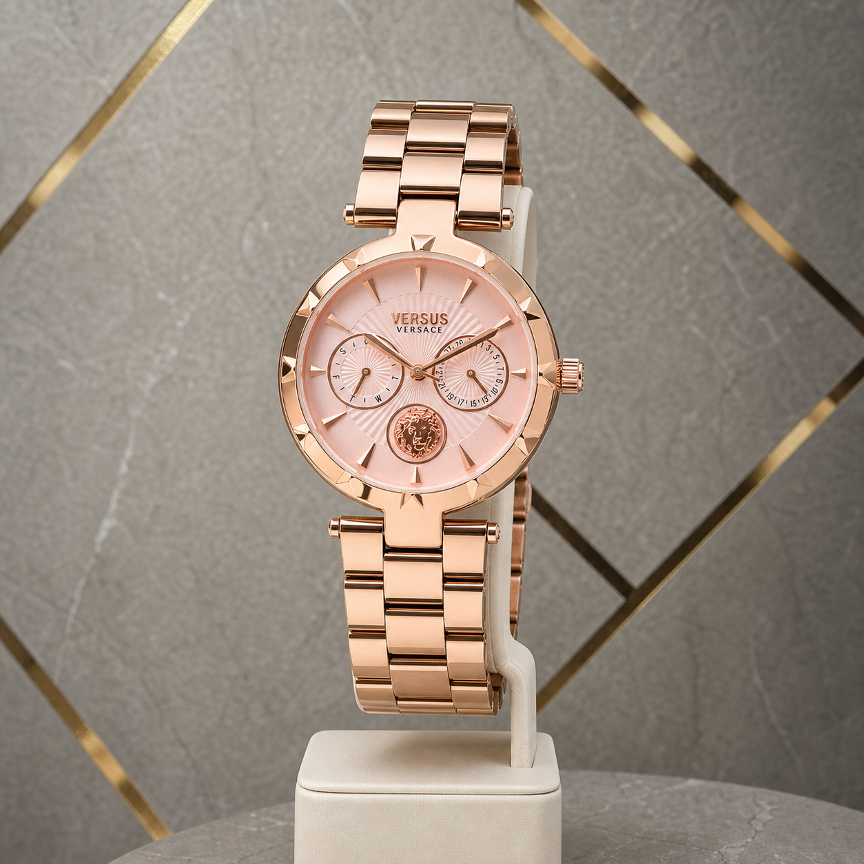 Versace Sertie rose-gold watch against gray and gold office wall